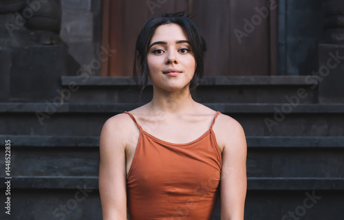 Young woman sitting in Butterfly Pose on stairs of temple