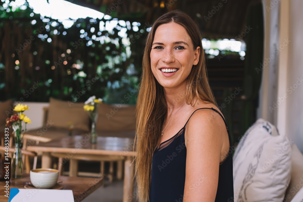 Happy lady sitting at wooden table with cup of coffee and notepad