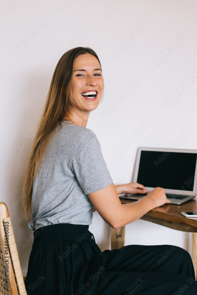 Cheerful woman browsing laptop in cafe on