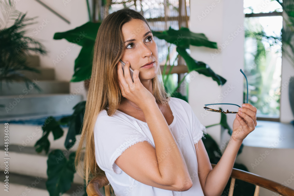 Beautiful woman talking on smartphone in cozy workspace