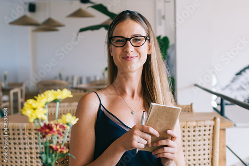 Obraz na płótnie Cheerful woman with book in hands sitting in cafe w salonie