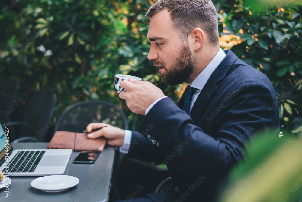Focused young male with laptop and coffee in cafe