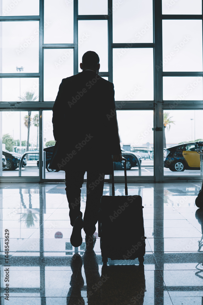 Anonymous man with luggage walking in airport