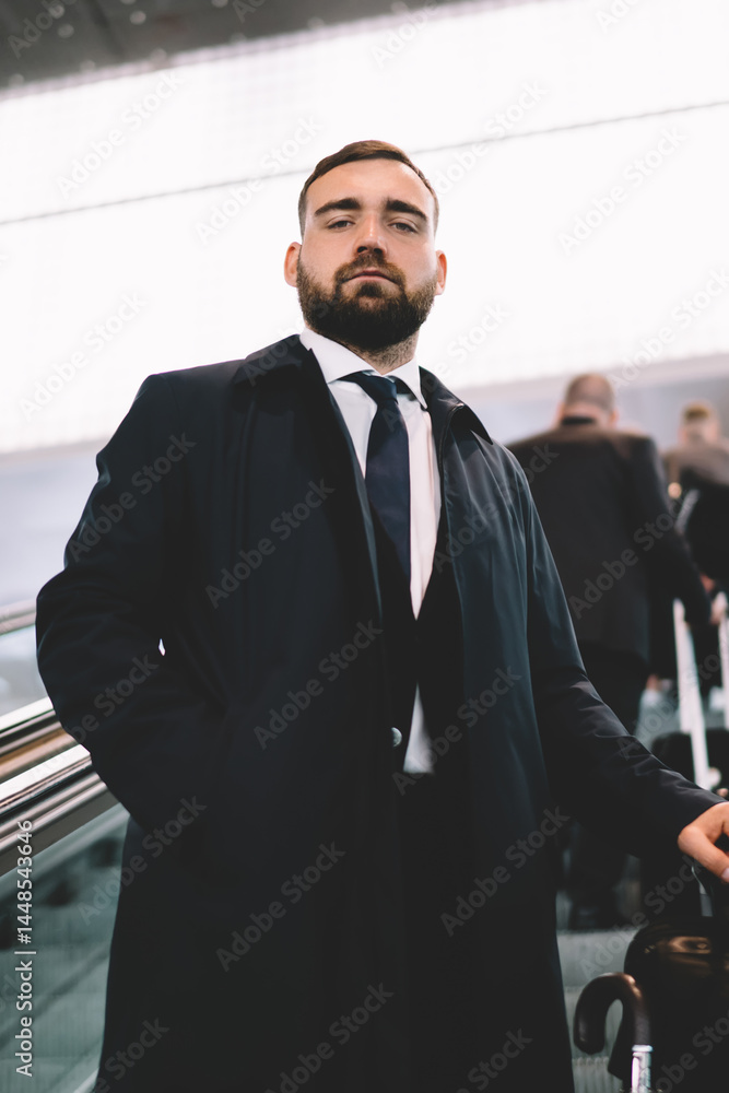 Serious man riding up escalator at airport