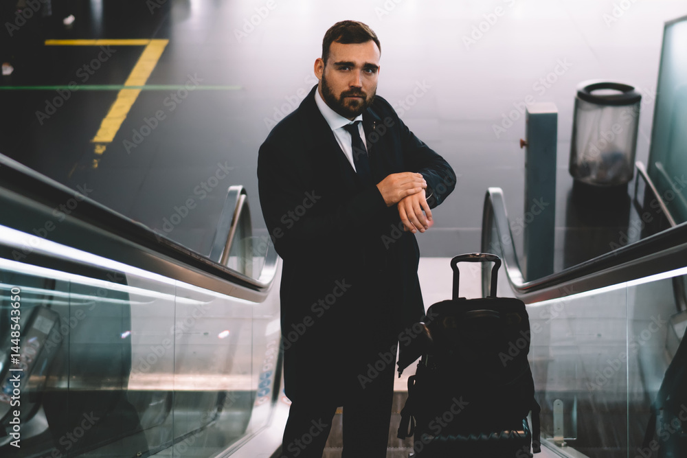 Serious businessman riding on moving stairs in airport