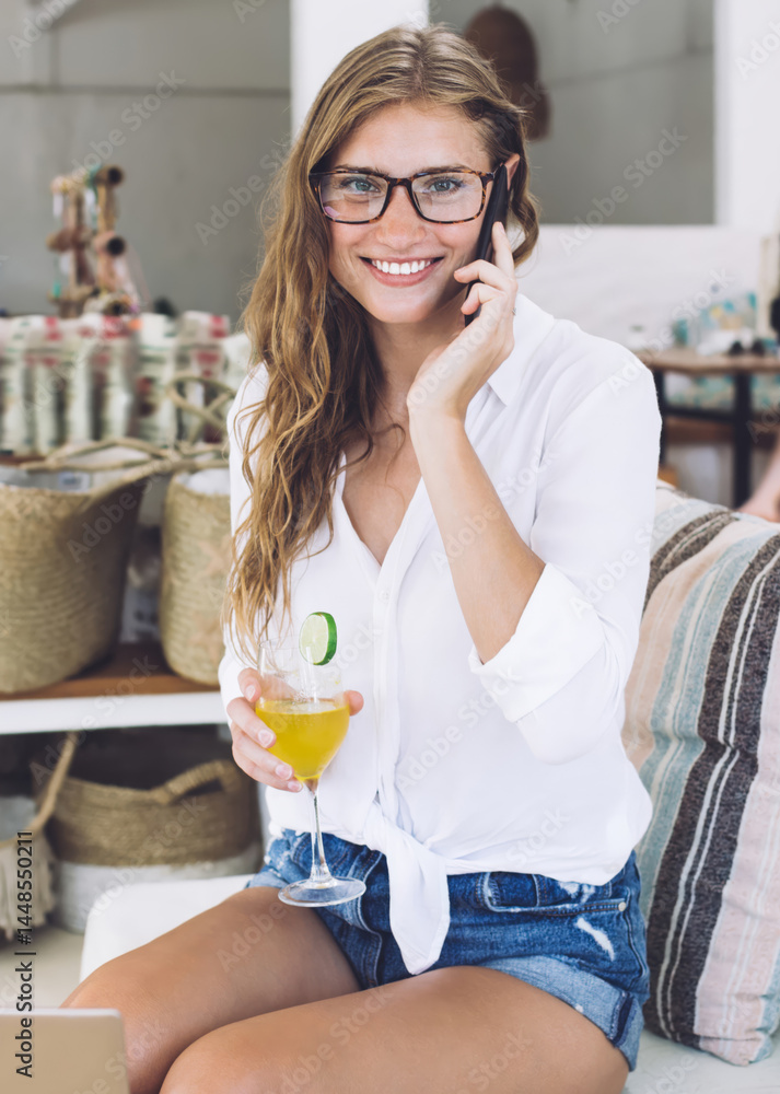 Optimistic woman relaxing in cafeteria while chatting on mobile