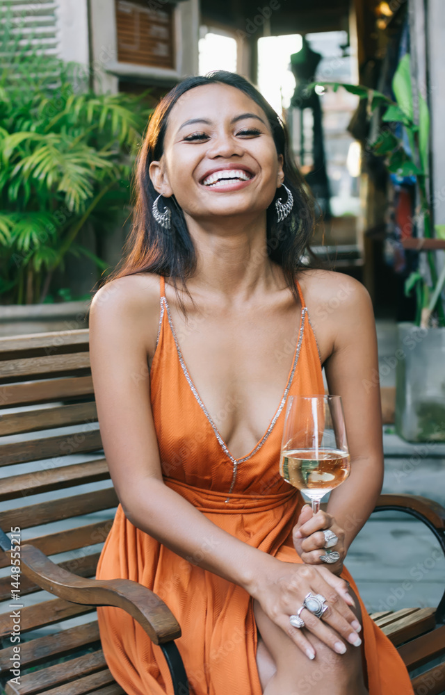 Cheerful young ethnic woman with glass of wine at tropical resor