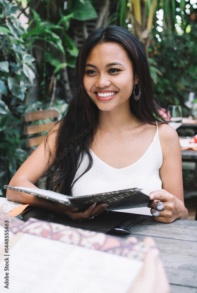Cheerful young woman with menu in outdoor cafe