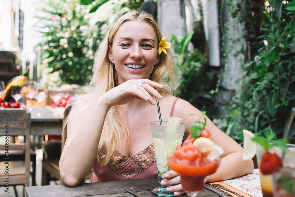 Cheerful woman enjoying cocktail in outdoor cafe