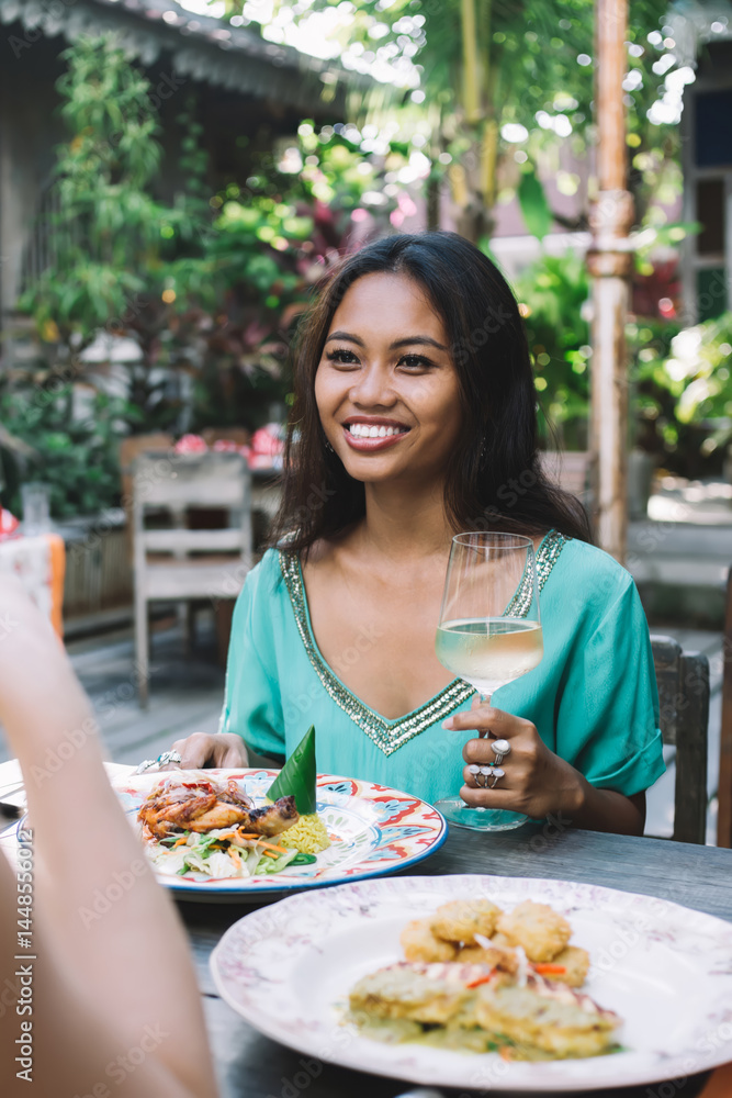 Positive women drinking wine in outdoor cafe
