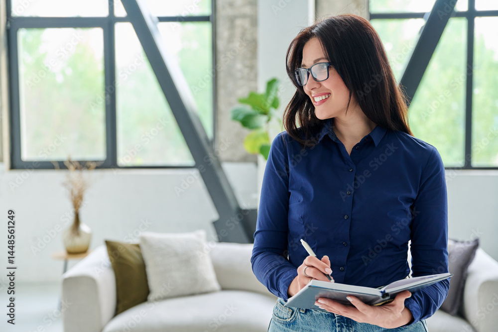 Portrait of smiling business woman with notebook in office with couch
