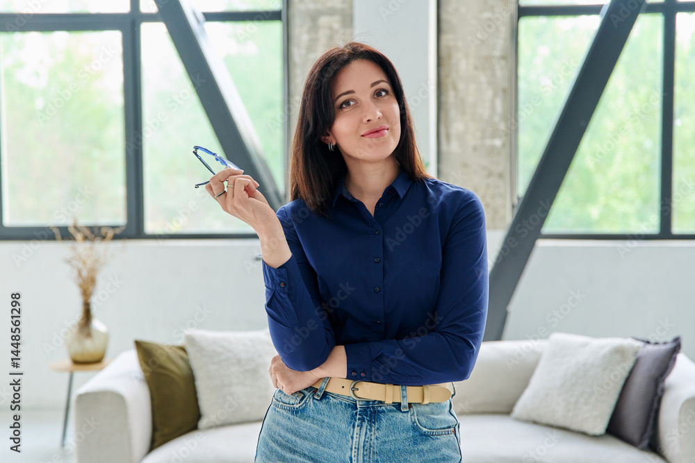 Portrait of young positive business woman looking at camera in office with couch