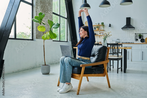 Tired satisfied woman working in chair with laptop, having break for relaxation, with arms raised up to sides.