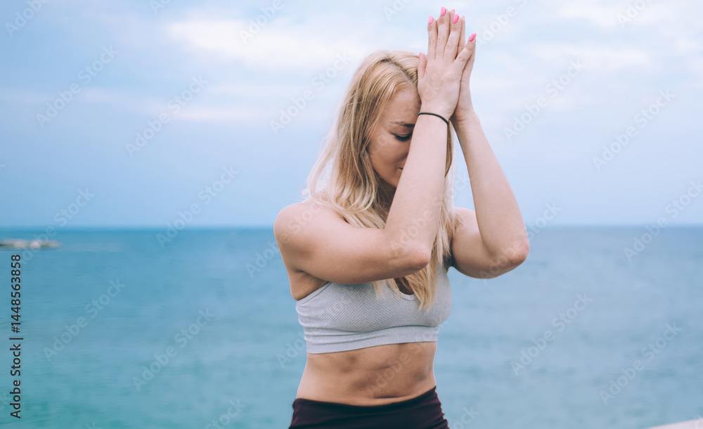 Caucasian woman calms brain minds with lotus yoga pose enjoying morning training near coastline, good looking female increases awareness and attentiveness with padmasana meditation exercise