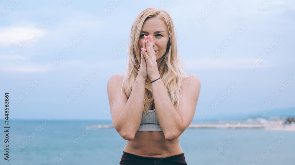Slim woman sitting in lotus pose near seafront