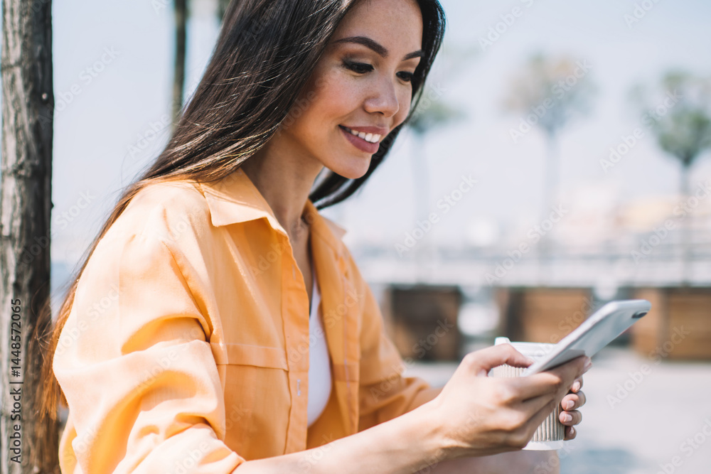 Ethnic woman browsing phone on city seafront