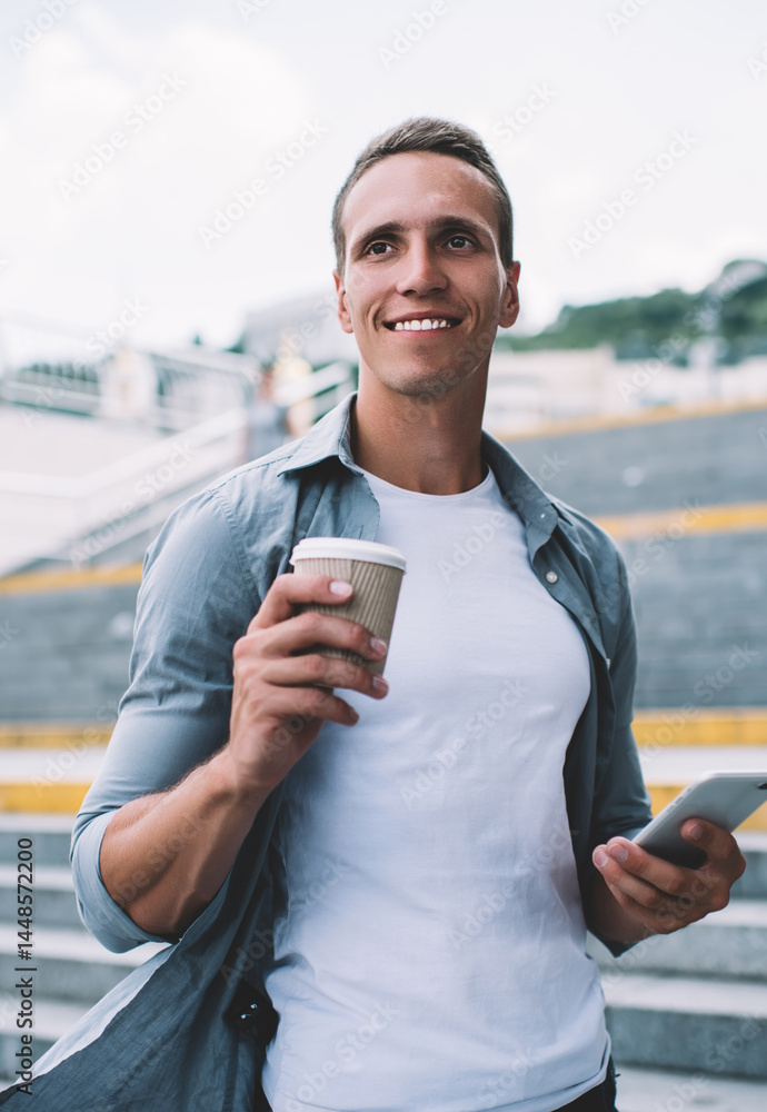 Content man standing with coffee cup on street stairs