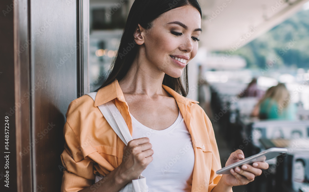 Smiling ethnic woman using smartphone in outdoors cafe