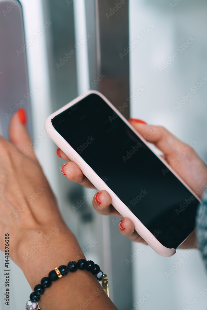 Cropped image of female's finder pressing buttons on electronic key panel checking code via smartphone modern application, woman unlocking door using gadgets to smart security home system