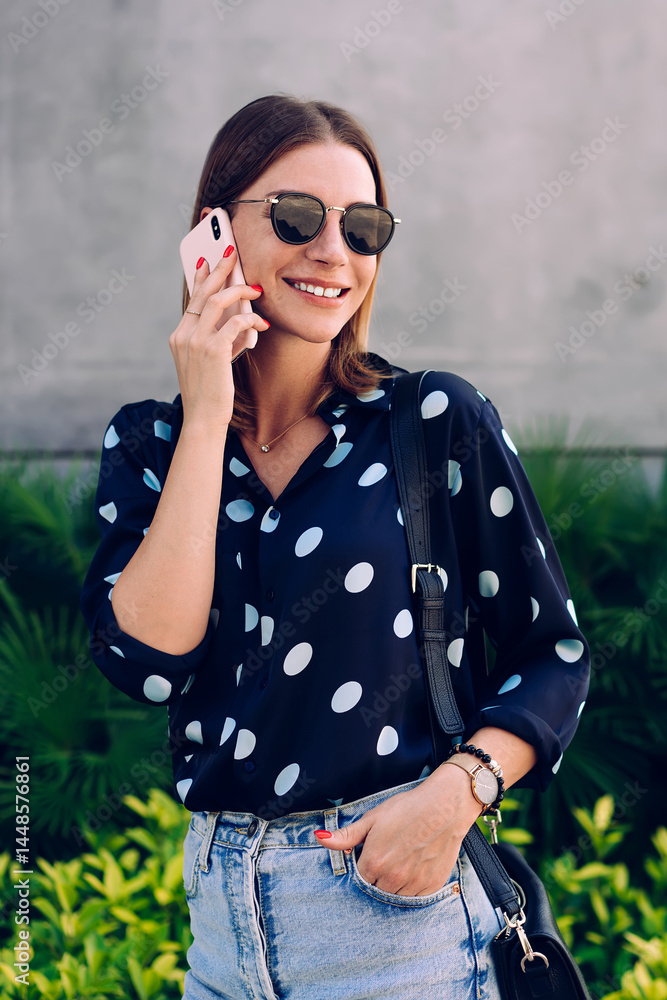 Cheerful woman speaking on smartphone on street