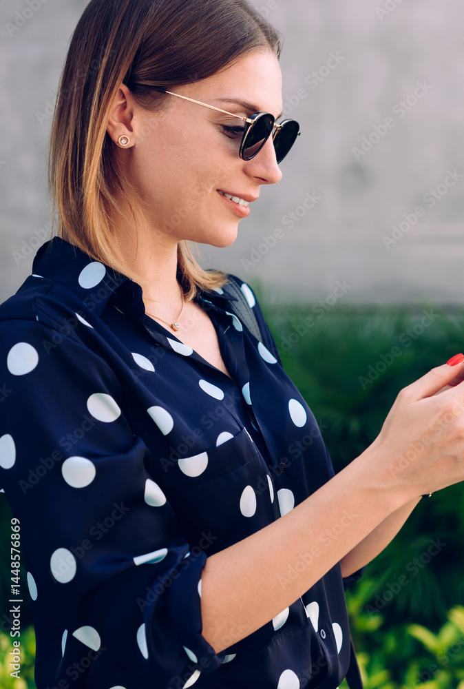 Positive woman browsing smartphone on street