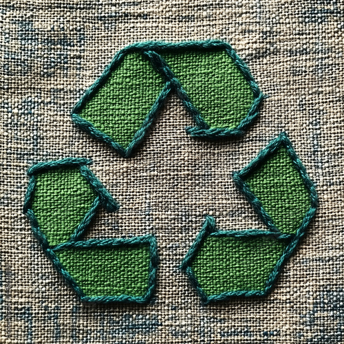 Obraz na płótnie Símbolo de reciclagem verde com costura detalhada e textura de linha visível. Ícone ecológico sobre fundo claro, representando conservação ambiental e design sustentável artesanal w salonie