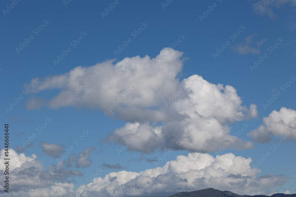 Fototapeta premium White cumulus clouds drifting across a vibrant blue sky