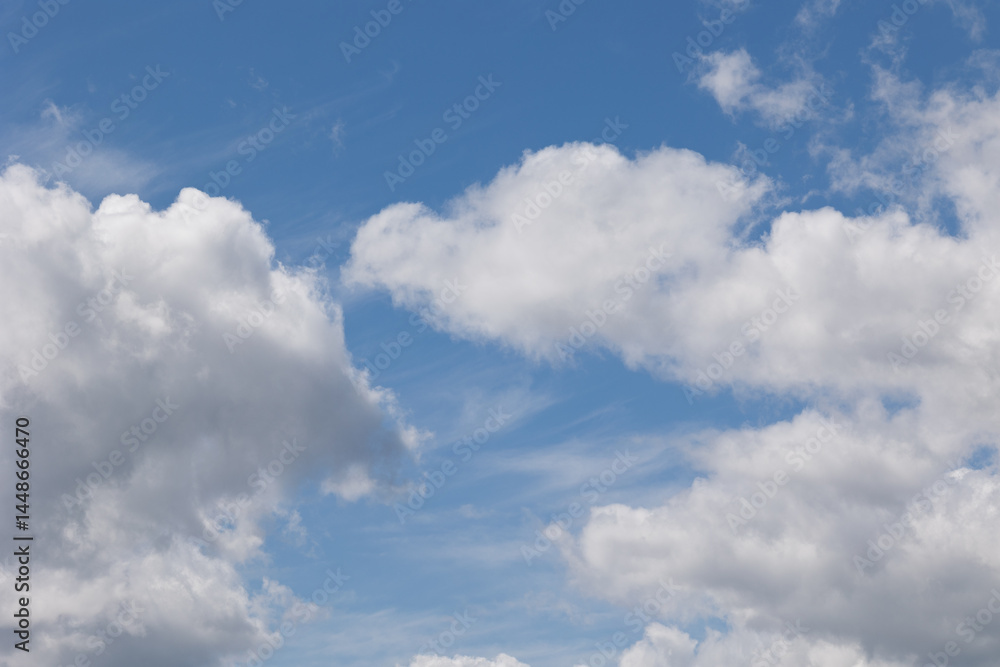 Fototapeta premium White cumulus clouds drifting across a vibrant blue sky