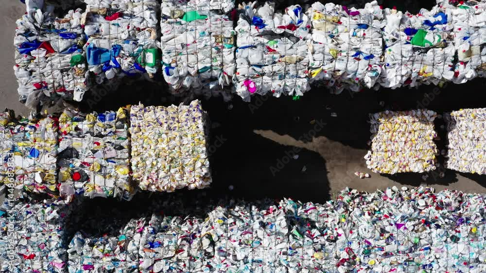Aerial view of sorted and compressed plastic waste bales at an outdoor recycling plant, illustrating large-scale waste management operations.