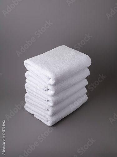 stack of white terry towels on grey background
