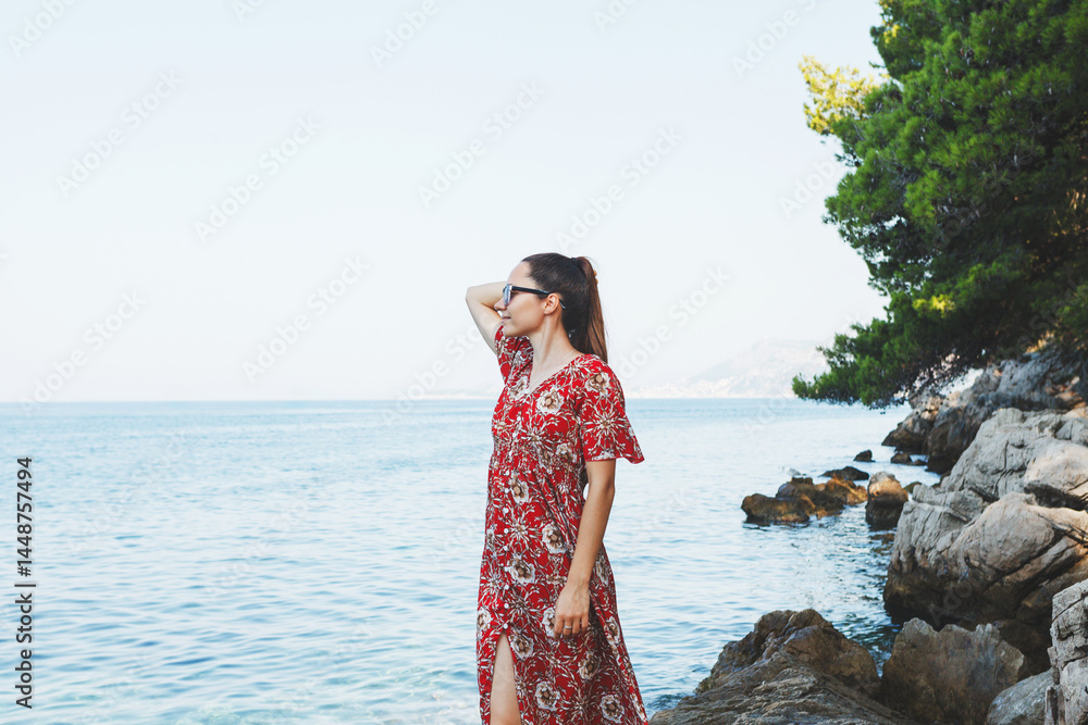 A woman is enjoying a beautiful and scenic coastal view while wearing a summer dress