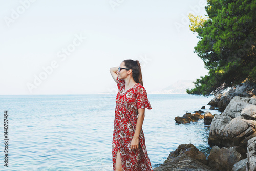 Obraz na płótnie A woman is enjoying a beautiful and scenic coastal view while wearing a summer dress w salonie