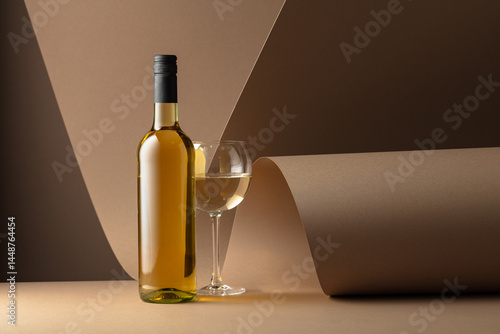 Obraz na plátne Bottle and glass of white wine on a beige background.