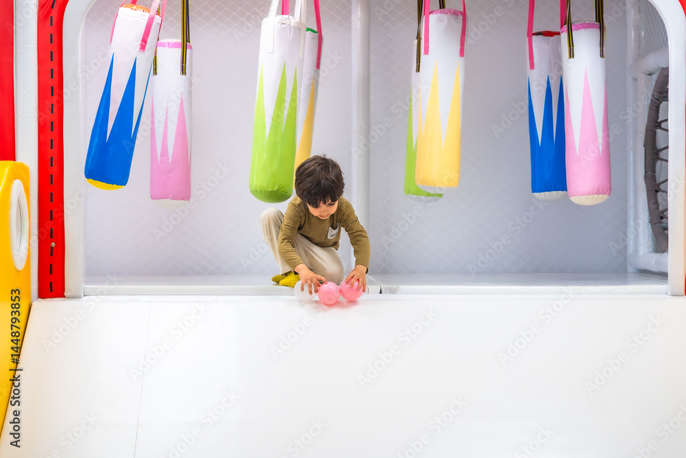 Boy playing with balls in soft play area with punching bags