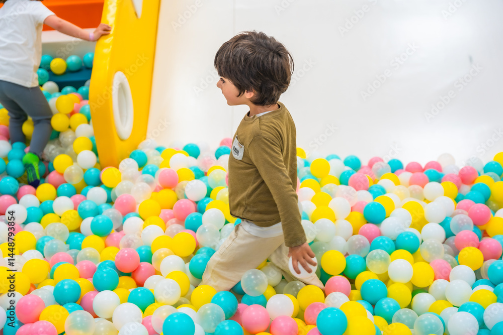 Child playing in ball pit, enjoying colorful playground fun