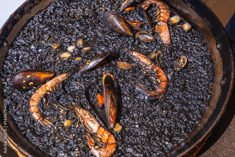 Delicious black paella with seafood and shrimp in a pan
