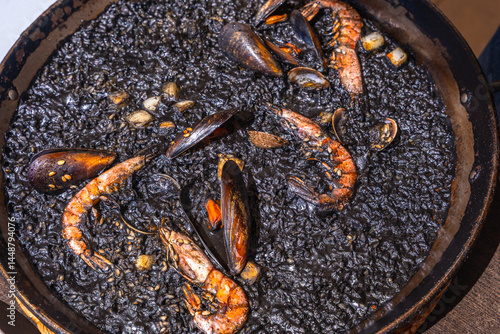 Delicious black paella with seafood and shrimp in a pan