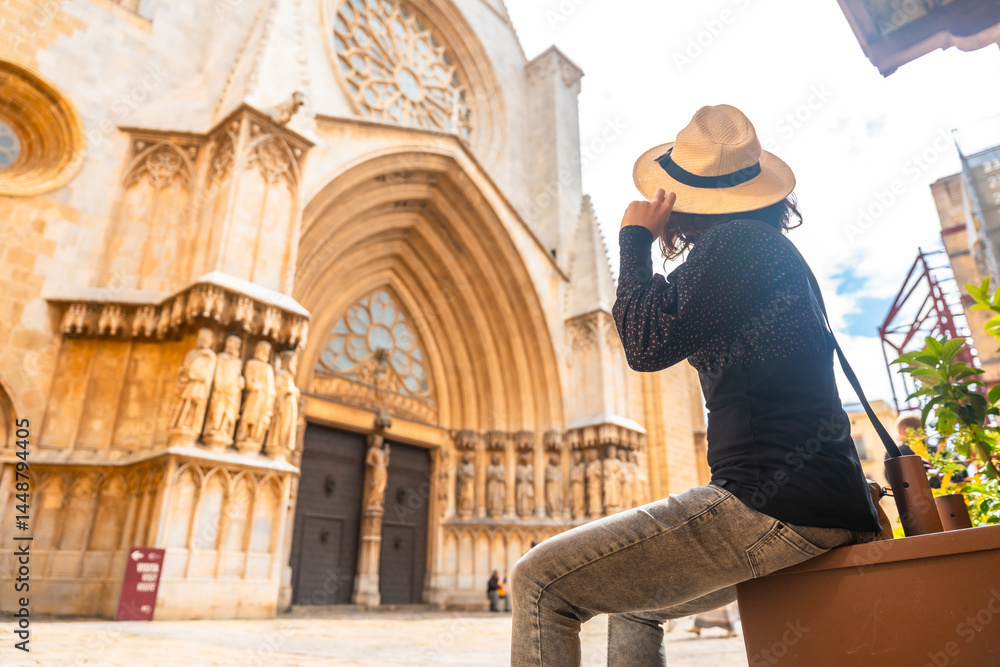 Tourist holding her hat while admiring tarragona cathedral in spain
