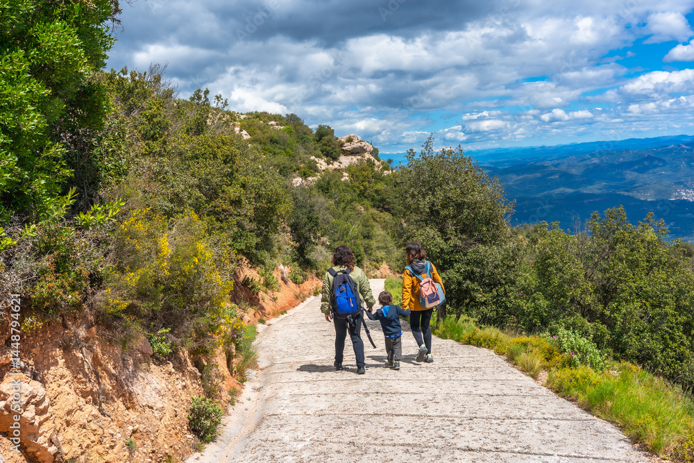 Fototapeta premium Family hiking in montserrat mountains near santa maria de montserrat abbey