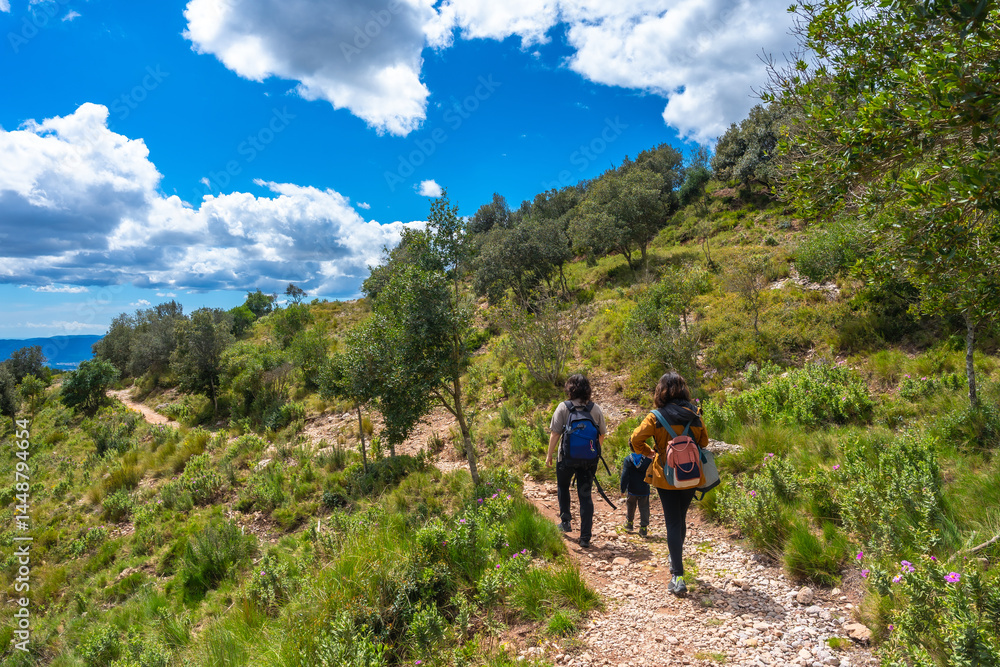 Tourists hiking in montserrat mountain on sunny day with blue sky and clouds