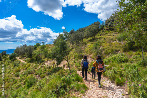 Obraz na płótnie Tourists hiking in montserrat mountain on sunny day with blue sky and clouds w salonie