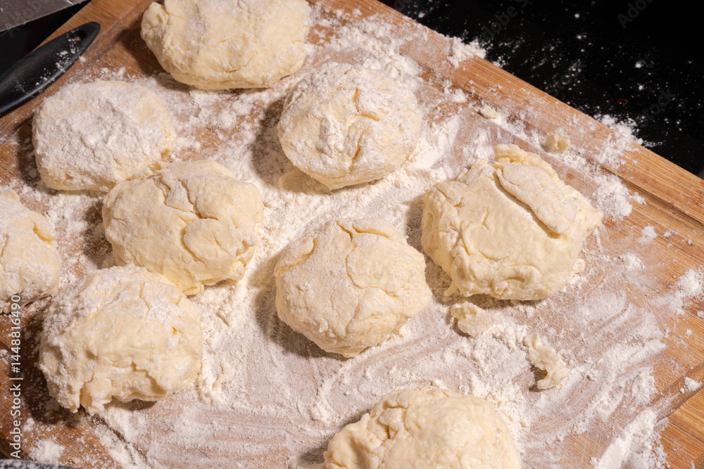 Irregularly shaped dough pieces dusted with flour rest on a wooden surface, ready for baking or cooking.
