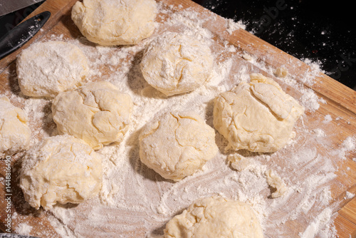 Irregularly shaped dough pieces dusted with flour rest on a wooden surface, ready for baking or cooking.