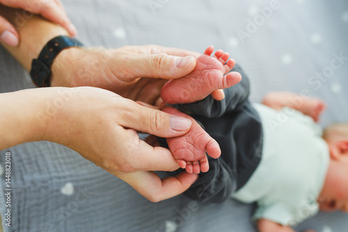Obraz na płótnie Close-up of baby feet in parent's hands. Baby feet with little toes. Cute photo of baby feet. w salonie