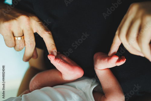 Obraz na płótnie Close-up of baby feet in parent's hands. Baby feet with little toes. Cute photo of baby feet. w salonie