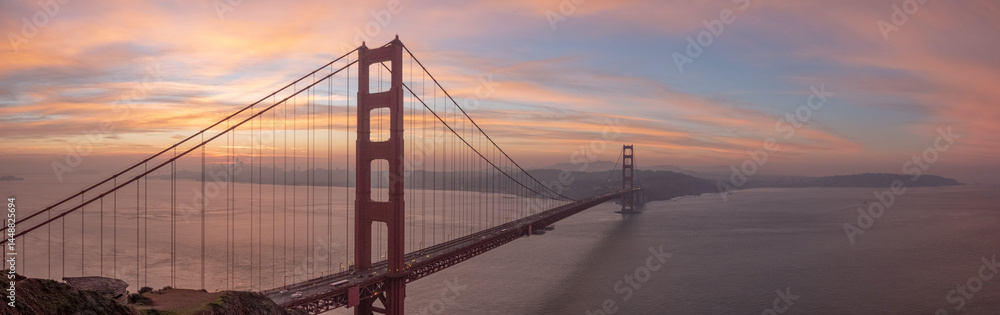 Obraz premium Golden Gate Bridge detail seen at sunrise with dramatic warm tones lighting fog and support cables, January 4, 2019, San Francisco, CA, USA