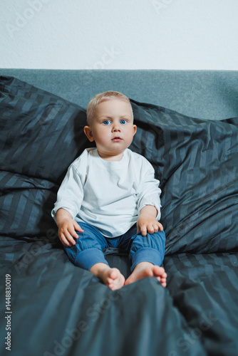 Obraz na płótnie Funny 2 year old little boy wearing pajamas resting and playing in bed. Little toddler boy playing in bed. w salonie