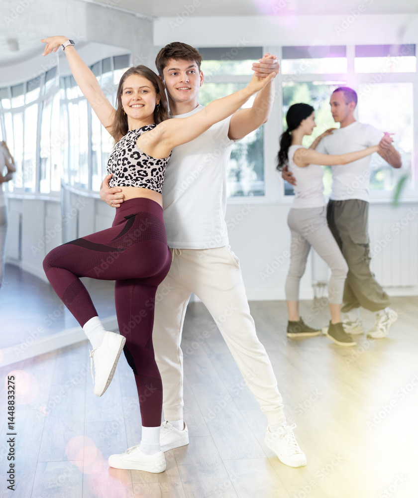 Fototapeta premium Happy young woman enjoying training dancing active swing with male partner in modern dance room. Social dancing concept