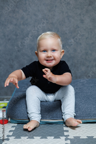 Obraz na płótnie Blue-eyed blond boy 2 years old playing at home in the room. Toddler boy smiling looking at the camera. Home clothes for children. w salonie
