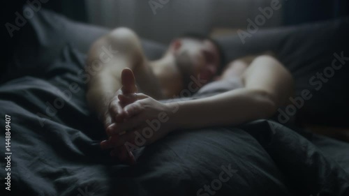Close-up of young spouses intertwining fingers and holding hands while peacefully snuggling in bed after sleep in morning, deep love, affection and intimacy, focus of hands
